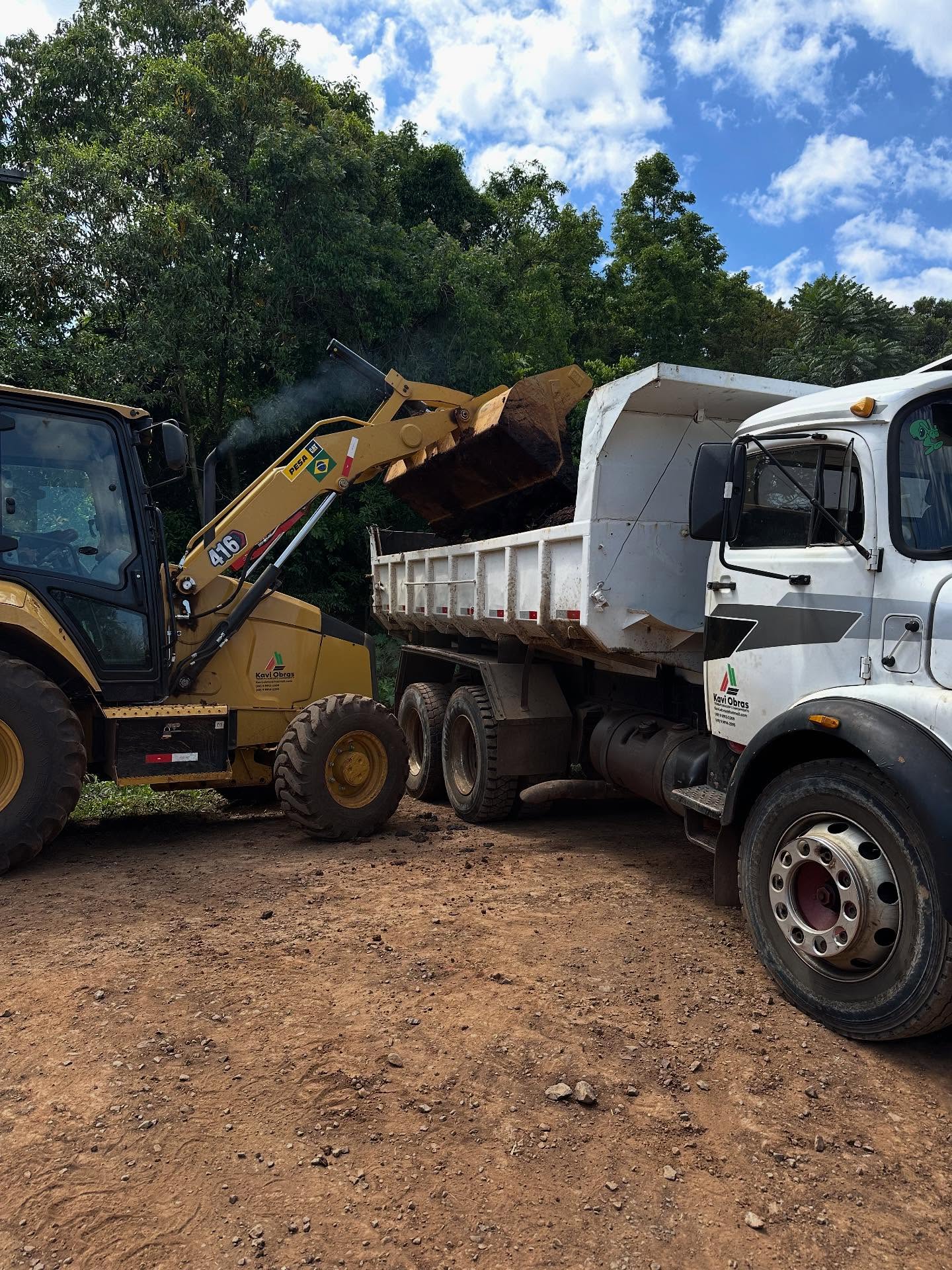 Retroescavadeira CAT carregando caminhão caçamba em corte de solo da Kavi Construções